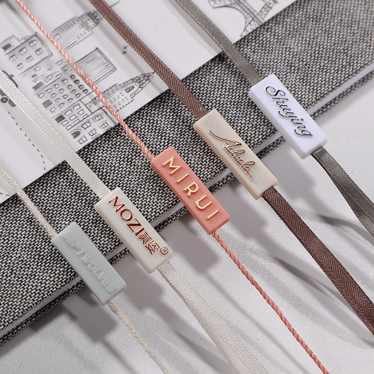 Close-up of black string loop attached to clothing hang tag, used in fashion packaging