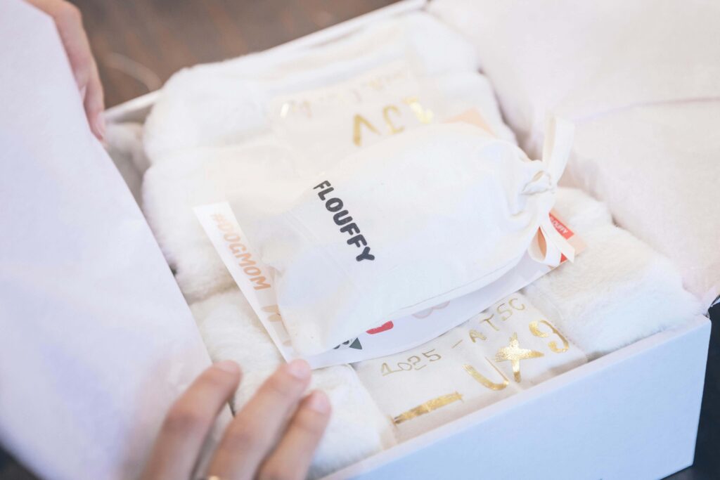 Branded unboxing experience with custom tissue paper, drawstring pouch, and promotional inserts inside a gift box.