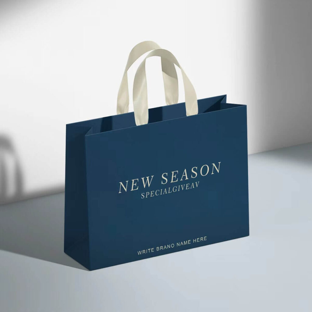 Printed paper bag with handles for clothing packaging – matte blue finish with white ribbon handles, perfect for boutique and seasonal promotions.