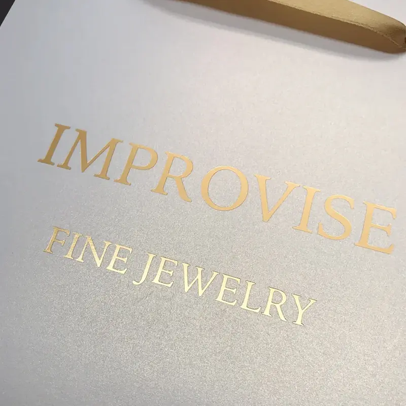 Close-up of gold foil logo stamping on a custom luxury paper bag for fine jewelry packaging, showing premium paper texture and refined brand finish.